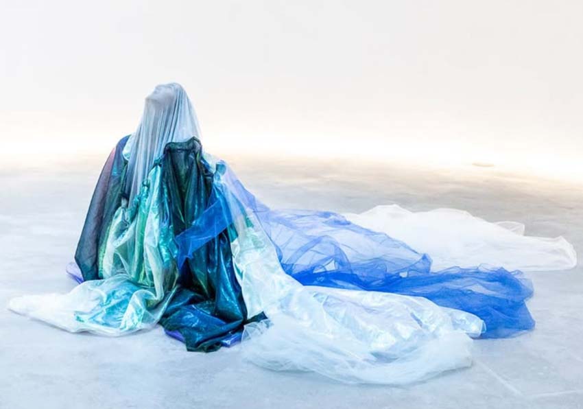 event image:A woman, completely covered, sitting on the ground looking up at the sky